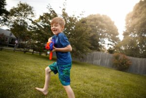 Boy playing with toy gun outdoors.