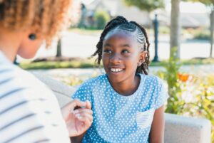 Woman and preteen talking on a bench.