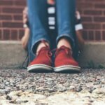 Closeup of bent legs of person sitting on a sidewalk.