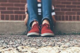 Closeup of bent legs of person sitting on a sidewalk.