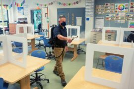 Janitor spraying cleaning agent in a classroom.