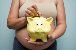 Pregnant woman holding yellow piggy bank.