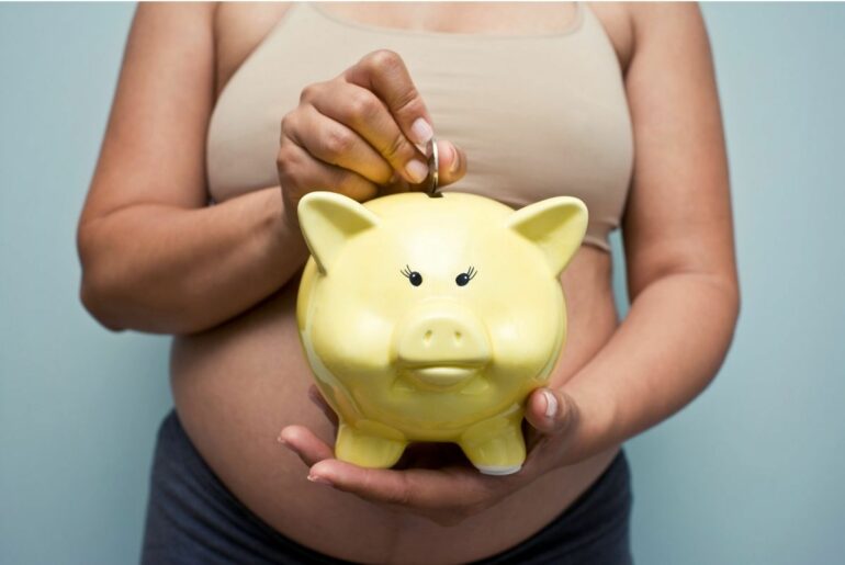 Pregnant woman holding yellow piggy bank.