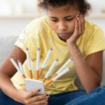 Tween girl looking at phone that has cigarrettes coming out of the screen.