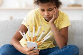 Tween girl looking at phone that has cigarrettes coming out of the screen.