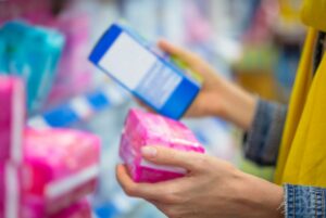 Close up of woman's hands at store holding period products.