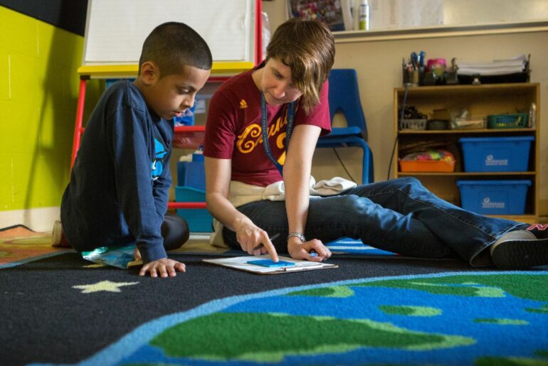 Teacher helping student on the floor.