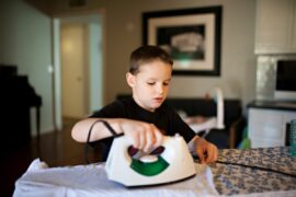 Young boy with a look of concentration using an iron by himself