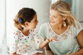 White child sitting next to mom and talking with hand gestures