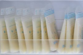 10 plastic breastmilk storage bags full of milk lined up in a refrigerator