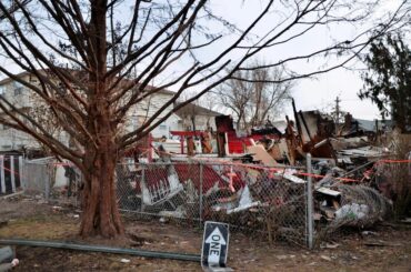A home completely destroyed by a hurricane, with a "One Way" sign fallen and warped on the ground in front of it