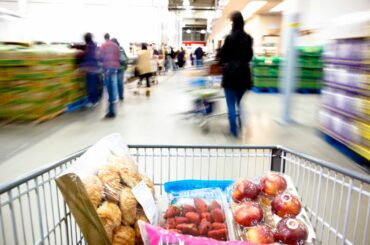 A shopping cart filled with food inside of a warehouse store