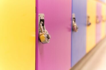 A closeup of a row of lockers in yellow, pink, and purple, with metal combination locks