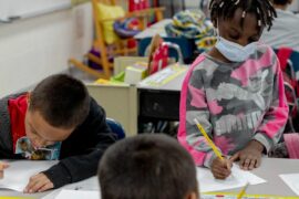 A diverse group of students works independently with pencils and paper in the classroom