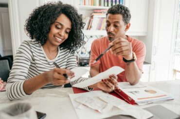 Two adults sitting next to each other looking at receipts and financial information