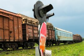 A stop sign and crossing signal in front of a freight train