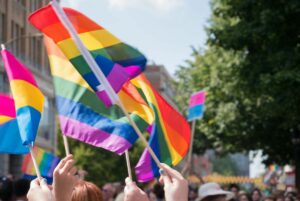 Hands holding rainbow flags at a Pride event.