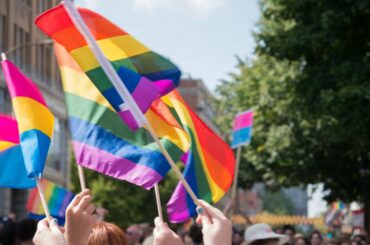 Hands holding rainbow flags at a Pride event.