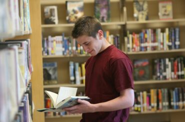 A teen browsing an informative LGBTQ+ book in the library.