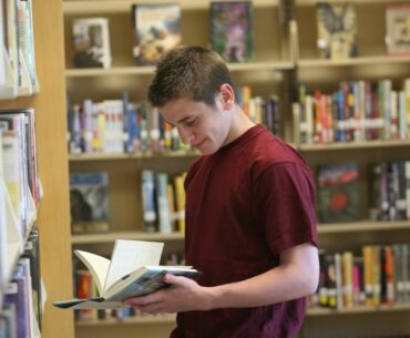 A teen browsing an informative LGBTQ+ book in the library.