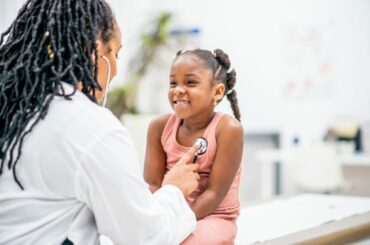 Child smiles as getting checked with stethoscope at a doctor's visit