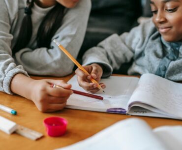 A child smiling and writing in a notebook as an example of good homework habits