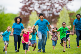 Summer camp counselors run across a field with kids