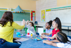 A teacher interacts with a diverse group of elementary school students in a classroom
