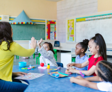 A teacher interacts with a diverse group of elementary school students in a classroom