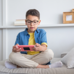 A child plays a game on a device while sitting on a couch
