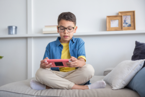 A child plays a game on a device while sitting on a couch