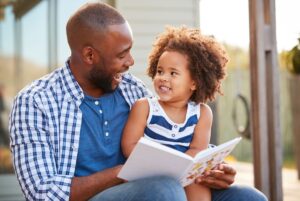Dad reading a book to a smiling child to represent why diverse books are important