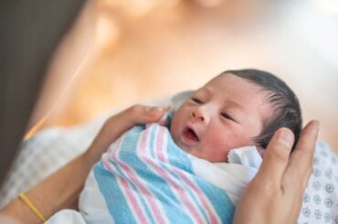 Newborn baby swaddled in hospital blanket