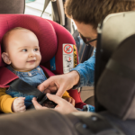 Dad buckling baby into car