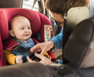 Dad buckling baby into car