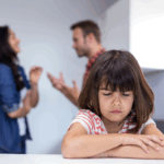 Sad child listening to parents argue