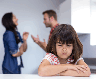 Sad child listening to parents argue