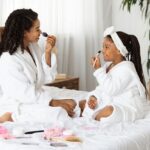 Mom and child in bathrobes putting on makeup together