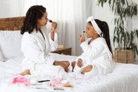 Mom and child in bathrobes putting on makeup together
