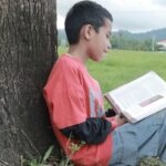 Boy reading book outdoors