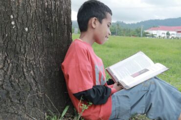 Boy reading book outdoors