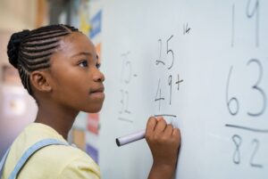 Kid solving math problems on board