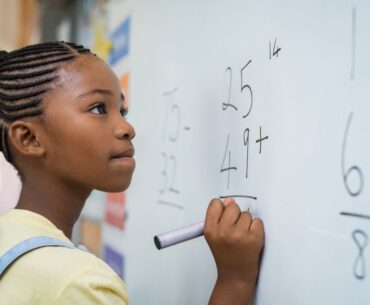 Kid solving math problems on board