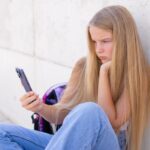 Teen staring at a smartphone to illustrate addictive design of social media