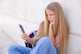 Teen staring at a smartphone to illustrate addictive design of social media