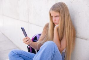 Teen staring at a smartphone to illustrate addictive design of social media