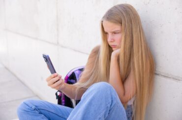 Teen staring at a smartphone to illustrate addictive design of social media