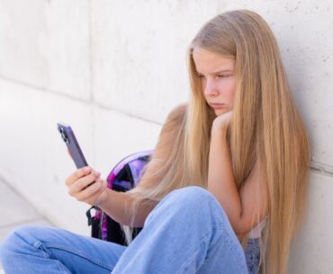Teen staring at a smartphone to illustrate addictive design of social media