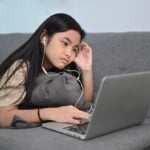 Teen playing game on laptop