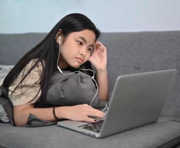 Teen playing game on laptop